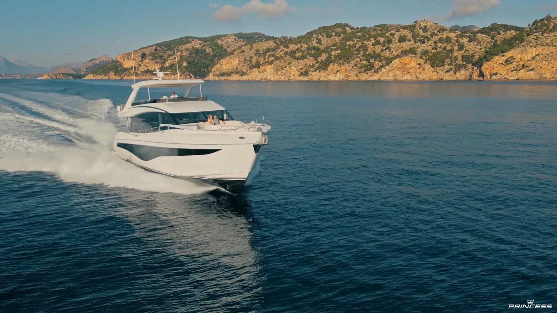 A row of luxury yachts moored in a marina below a hillside town